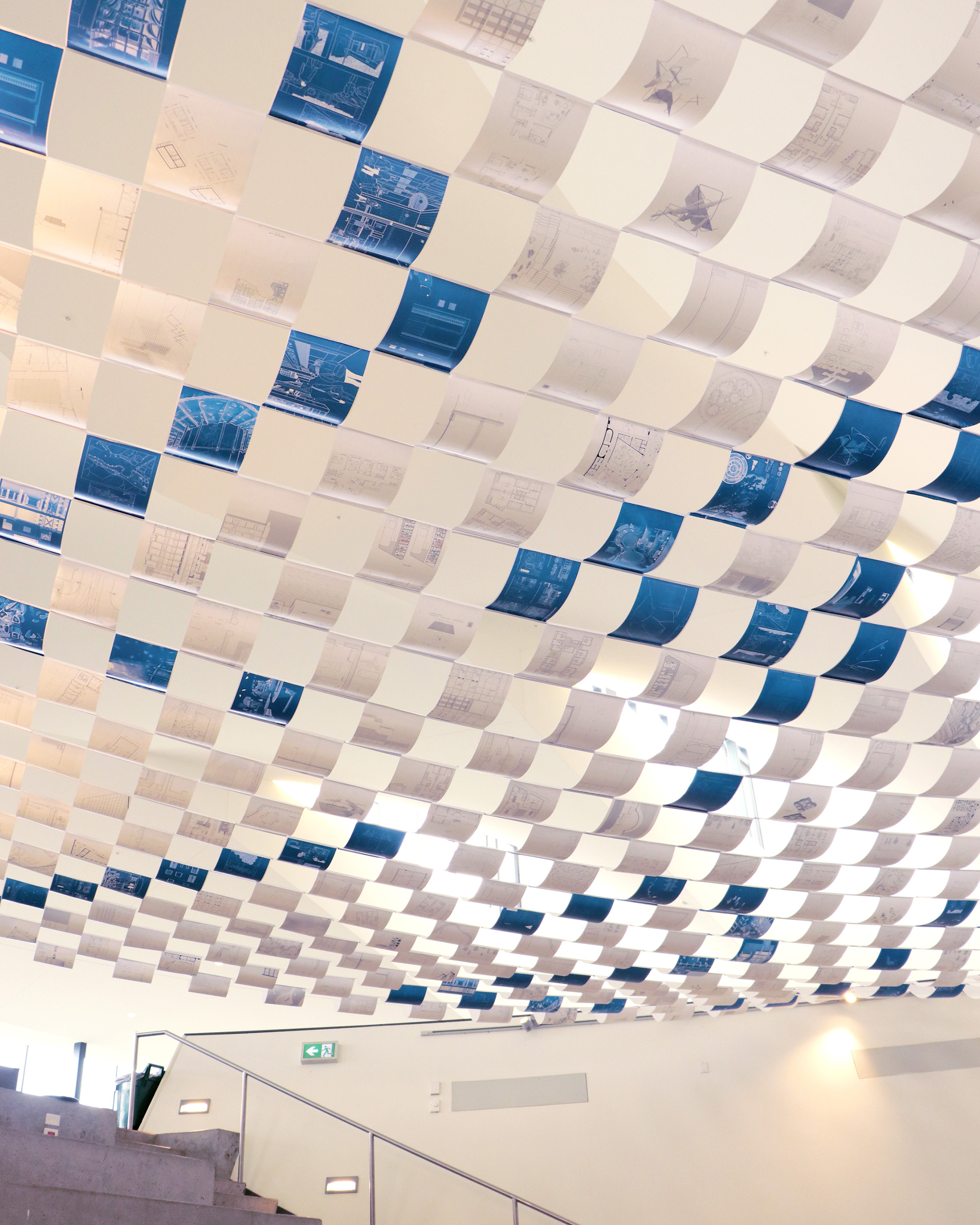 Photo of a canopy of drawings arranged in a grid. Some are on a blue background and arranged in a way that 24/25 is shown when viewed from a certain angle.