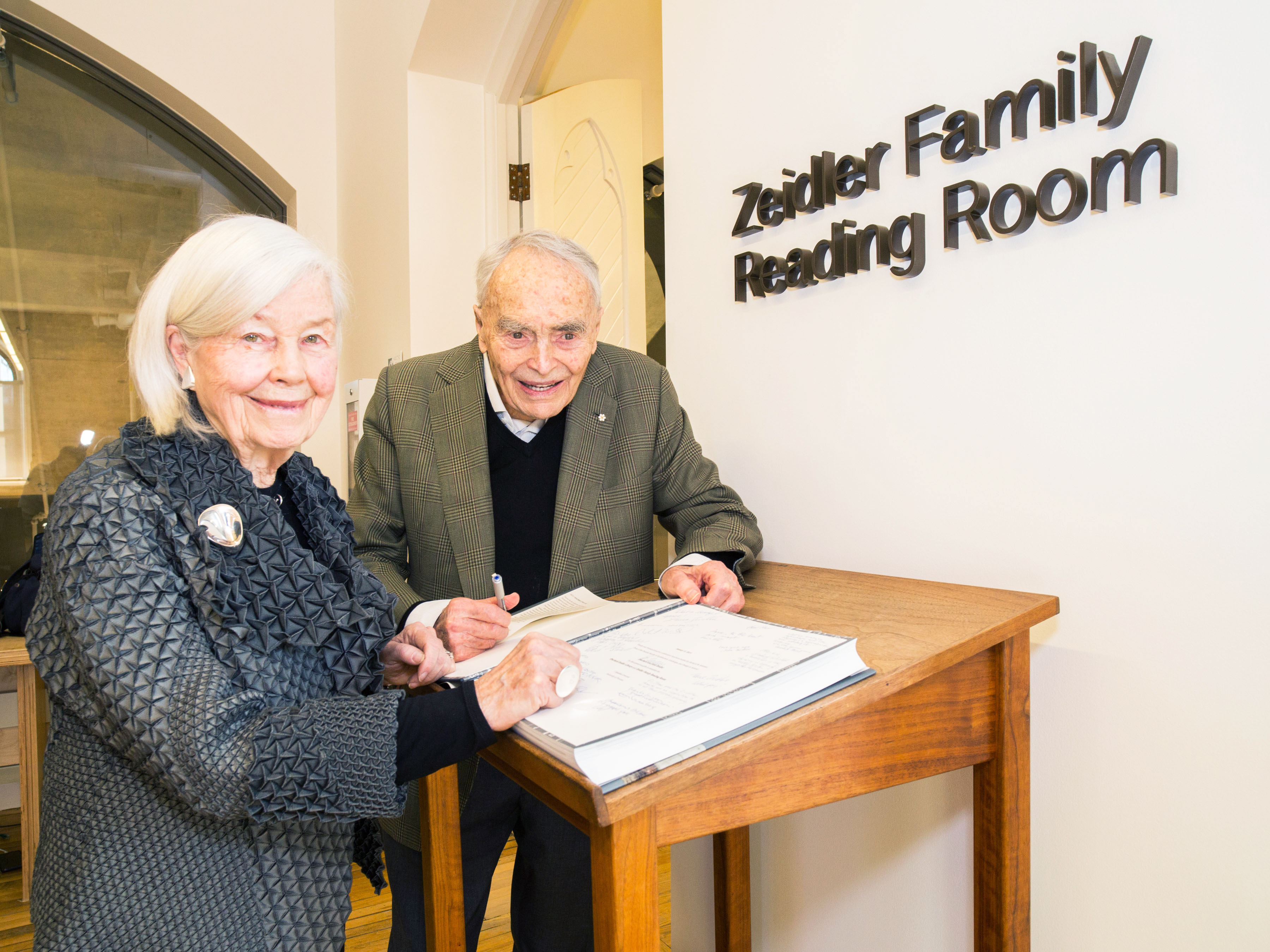 Dr. Eberhard Zeidler and Mrs. Jane Zeidler sign the guestbook at the Zeidler Family Reading Room of the Eberhard Zeidler Library in 2019